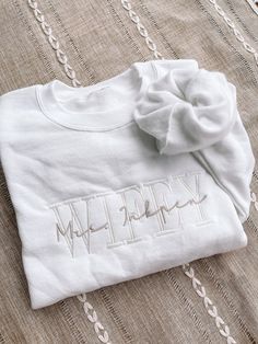 Personalized Embroidered Wife Sweatshirt with name. Embroidery size: approximately 8.5" in length (across chest) Sizes: UNISEX Small, Medium, Large, XLarge, 2Xlarge, 3XLarge -Fit is a little loose -Not pre-shrunk -See size guide in the photos -50/50 cotton/poly Color: sweatshirt White Thread color: White (for main wording) Light Beige (for Mrs. *last name*) (colors cannot be changed) Font of embroidery: As shown in photos (this cannot be change) Text for main embroidery: Wife, Wifey, Bride, Future, Hubby, or Groom Text for secondary overlapping embroidery: Mrs. *last name* or Mr. *last name* (PLEASE SPECIFY if it is Mrs. or Mr. in the personalization box, we will assume it is Mrs. if there is no abbreviation). MATCHING HUBBY or WIFE SWEATSHIRT IN BLACK: https://www.etsy.com/listing/1269675 Wife Sweatshirt, Wifey Sweatshirt, Name Sweatshirt, Color Sweatshirt, Name Embroidery, Future Wedding Plans, Sweatshirt White, Bride Clothes, Wedding Goals