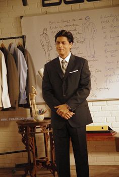 a man standing in front of a whiteboard with writing on it and wearing a suit