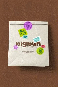 a paper bag with stickers on it sitting against a brown background that says bigburn