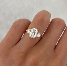 a woman's hand holding a three stone ring