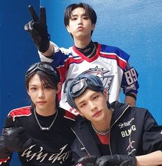 three young men sitting next to each other in front of a blue wall wearing black gloves