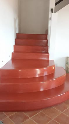 a set of red steps leading up to a door in a room with tile flooring