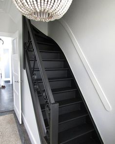 the stairs are black and white in this house with chandelier hanging from the ceiling