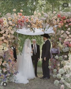 a man and woman standing under a floral arch