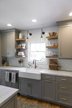 a kitchen with gray cabinets and white counter tops, an arrow pointing to the left