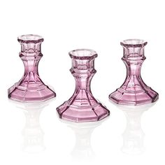 three pink glass candlesticks sitting next to each other