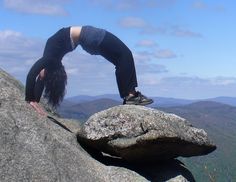 a woman standing on top of a large rock with her hands in the air as she climbs it