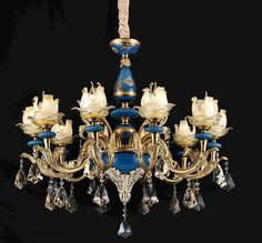 a blue and gold chandelier with white roses on the bottom, surrounded by crystal drops