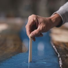 a person is holding a stick in their hand while standing on a blue surface with water