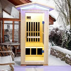 an outdoor sauna in the snow next to some chairs and a table with two chairs on it