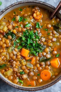 a bowl of soup with carrots, chickpeas and spinach in it