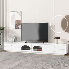 a flat screen tv sitting on top of a white entertainment center next to a potted plant