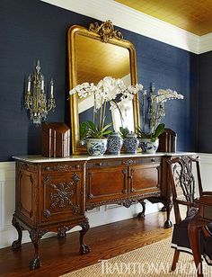 a large mirror sitting on top of a wooden dresser next to a vase filled with flowers