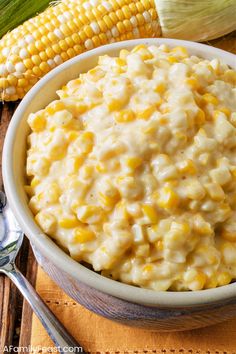 a bowl filled with macaroni and cheese next to corn on the cob