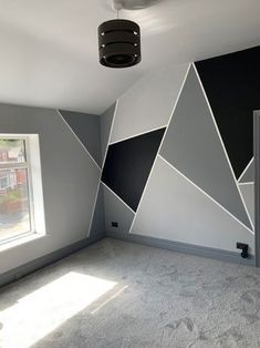 an empty room with grey walls and black and white geometric design on the wall,