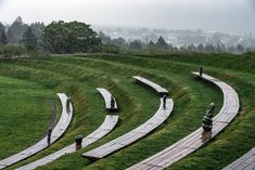 an empty field with benches in the middle and people standing on top of one hill