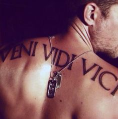 the back of a man's neck with tattoos on it that say, veni vidi vicci