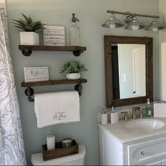 a bathroom with two shelves above the toilet and a mirror over the sink in front of it