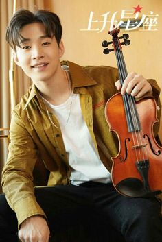 a young man sitting down holding a violin