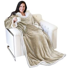 a woman is sitting on a couch wrapped in a blanket and holding a coffee cup