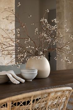 the table is set with plates, bowls and flowers in vases on top of it