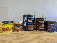 five cans of wood stain sitting on top of a wooden table