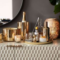 a table topped with lots of different types of bottles and glasses next to a mirror