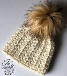 a white knitted hat with a brown fur pom