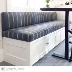 a white bench sitting under a window next to a table