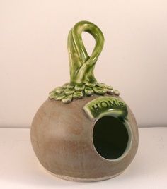 a ceramic vase with an animal's head sticking out of the top, on a white surface