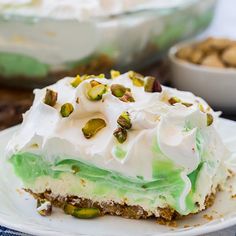 a piece of cake on a white plate with pistachios and whipped cream