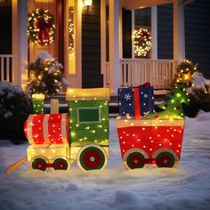 a christmas train with presents on it in front of a house decorated for the holidays