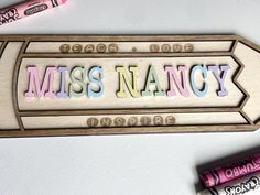 a wooden sign that says miss nancy next to some crayons and glue