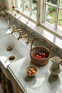 a basket of tomatoes sitting on top of a kitchen counter next to a white sink