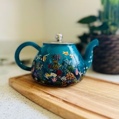 a blue teapot sitting on top of a wooden tray next to a potted plant