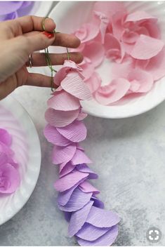 a person is holding flowers in front of two bowls filled with pink and purple petals