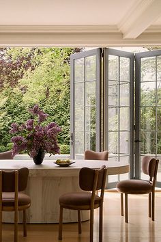 a dining room table with chairs and a vase filled with flowers on top of it