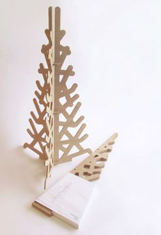 a wooden christmas tree next to an open book on a white surface with other items in the background