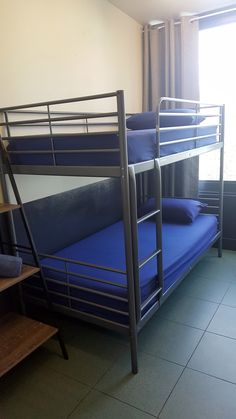 bunk beds are lined up against the wall in a room with tile flooring and windows