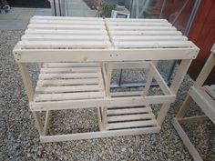 a table made out of wooden slats sitting on top of gravel next to a building