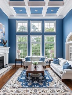 a living room with blue walls, white furniture and a fireplace in the center area