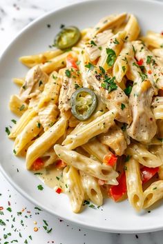 a white plate topped with pasta covered in sauce and chicken meat, garnished with parsley