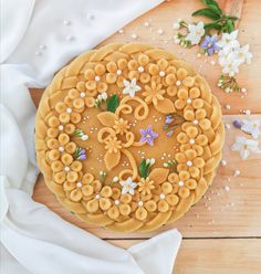 a cake decorated with flowers and icing on a wooden table next to white cloth