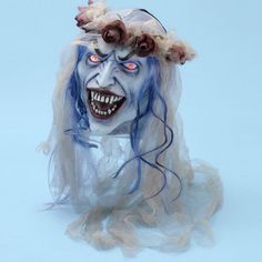 a creepy doll with blue hair and flowers on it's head is posed in front of a light blue background