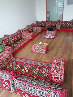 a living room filled with lots of red couches and rugs on the floor