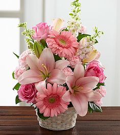 a basket filled with pink flowers on top of a wooden table