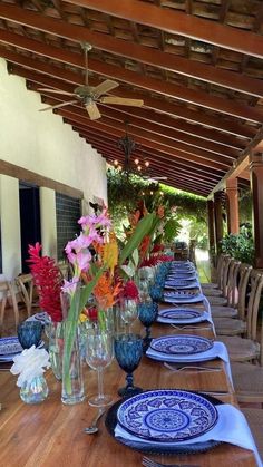 a long table set with blue and white plates, vases filled with colorful flowers