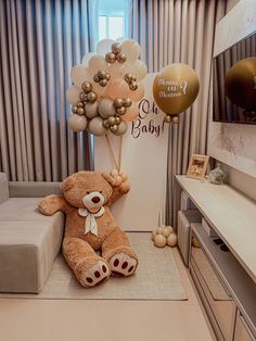 a teddy bear sitting on top of a couch next to balloons in the shape of animals