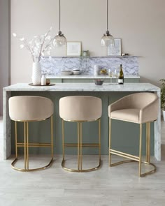 two bar stools sitting in front of a marble counter top with gold legs and barstools