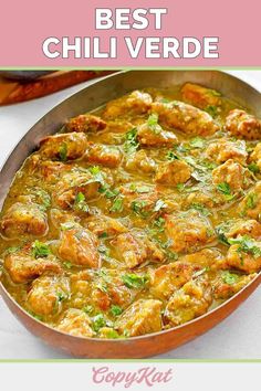 a pan filled with meat and vegetables on top of a white table next to a pink napkin